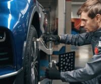 Mechanic performing wheel alignment on car using precision equipment