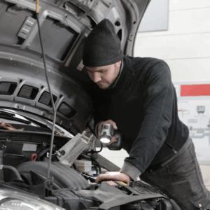 Auto technician checking AC gauges and refrigerant levels