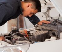 Mechanic inspecting car transmission in repair shop