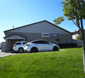 A small commercial building with two white SUVs parked outside, and signs for "Ace Auto" and "American Family Insurance" on the exterior wall.